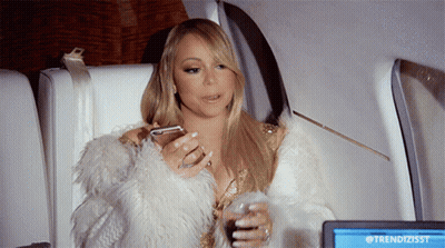 A Woman In A Fur Coat Is Sitting In Front Of A Screen That Says Trendizisst On It GIF