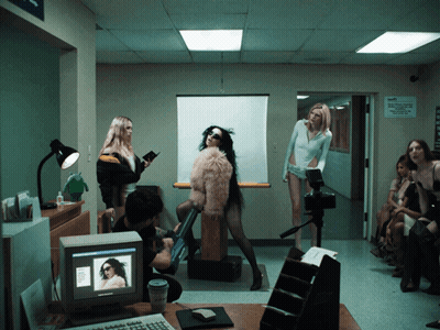 A Woman In A Fur Coat Is Standing In Front Of A Computer Screen GIF