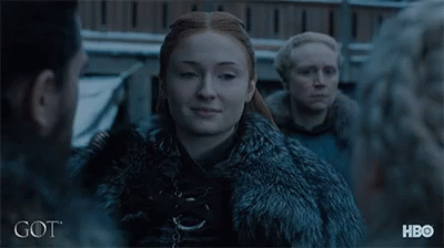 A Woman In A Fur Coat Is Standing In Front Of A Group Of People And The Word Got Is On The Bottom GIF