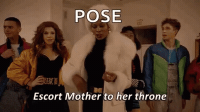 A Woman In A Fur Coat Is Standing In Front Of A Group Of People In A Room . GIF
