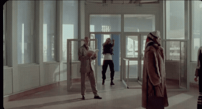 A Woman In A Fur Coat Stands In Front Of A Door That Says Tm GIF