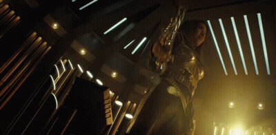 A Woman In A Futuristic Outfit Is Holding A Sword In A Dark Room GIF