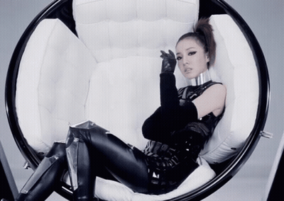 A Woman In A Futuristic Outfit Is Sitting On A Chair GIF