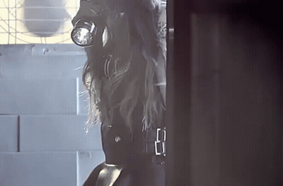 A Woman In A Gas Mask Is Standing In A Doorway GIF