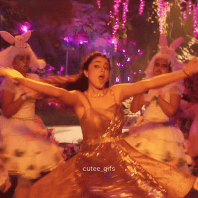A Woman In A Gold Dress Is Dancing With Her Arms Outstretched And The Caption Cutee_gifs Is Below Her GIF