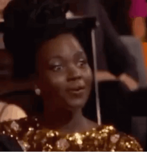 A Woman In A Gold Dress Is Making A Funny Face . GIF