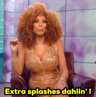 A Woman In A Gold Dress Is Sitting In A Chair And Saying Extra Splashes Dahlin ' ! GIF