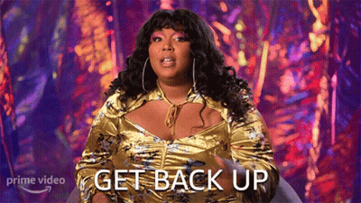A Woman In A Gold Dress Is Sitting In A Chair And Says Get Back Up GIF