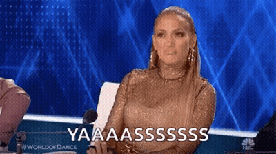 A Woman In A Gold Dress Is Sitting In Front Of A Microphone On A Stage And Making A Funny Face . GIF