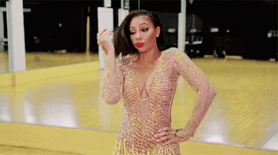 A Woman In A Gold Dress Is Standing In Front Of A Mirror In A Gym . GIF