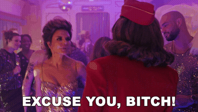 A Woman In A Gold Dress Is Standing Next To A Woman In A Red Hat And Says Excuse You Bitch . GIF