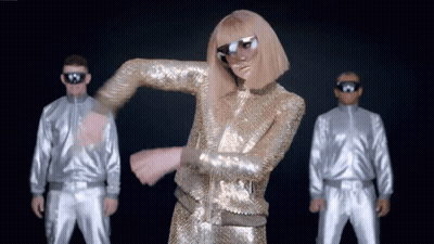 A Woman In A Gold Sequined Outfit Is Dancing In Front Of Two Men In Silver Suits GIF