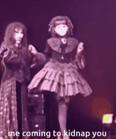 A Woman In A Gothic Dress Is Standing Next To Another Woman In A Purple Dress . GIF