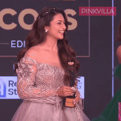 A Woman In A Gown Is Smiling And Holding A Bottle Of Champagne GIF