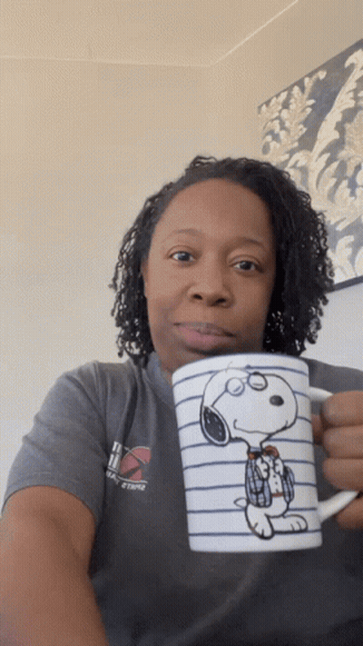 A Woman In A Gray Shirt Holds A Snoopy Coffee Mug GIF