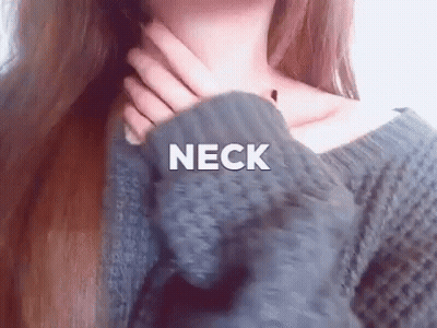 A Woman In A Gray Sweater Is Holding Her Neck . GIF