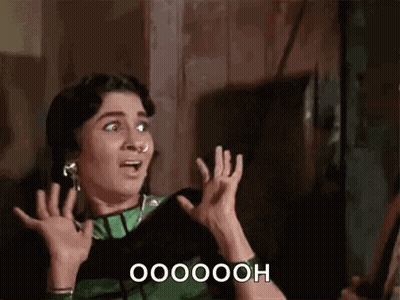 A Woman In A Green And Black Dress Is Making A Surprised Face And Holding Her Hands Up . GIF