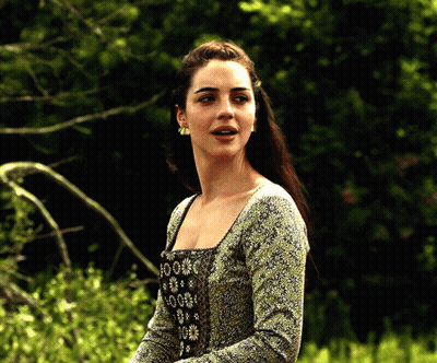 A Woman In A Green And Black Dress Is Standing In A Field GIF