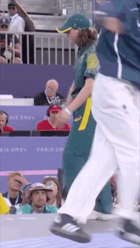 A Woman In A Green And Yellow Uniform Is Walking In Front Of A Crowd At A Sports Event . GIF