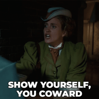 A Woman In A Green Coat And Hat Says " Show Yourself You Coward " GIF