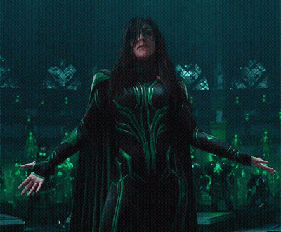 A Woman In A Green Costume Is Standing In A Dark Room GIF