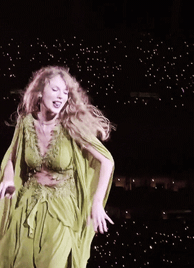 A Woman In A Green Dress Dancing On A Stage GIF
