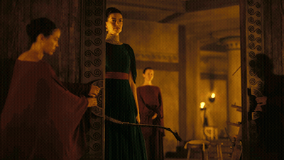 A Woman In A Green Dress Holds A Sword In A Dark Room GIF