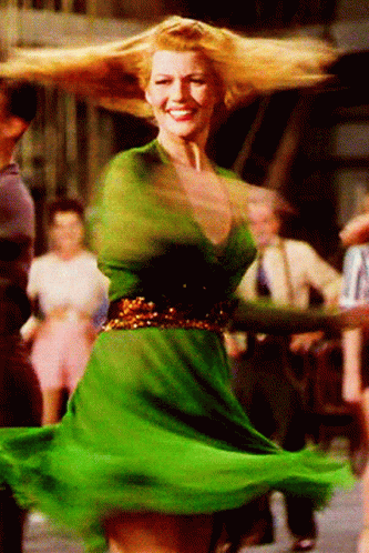 A Woman In A Green Dress Is Dancing And Smiling GIF