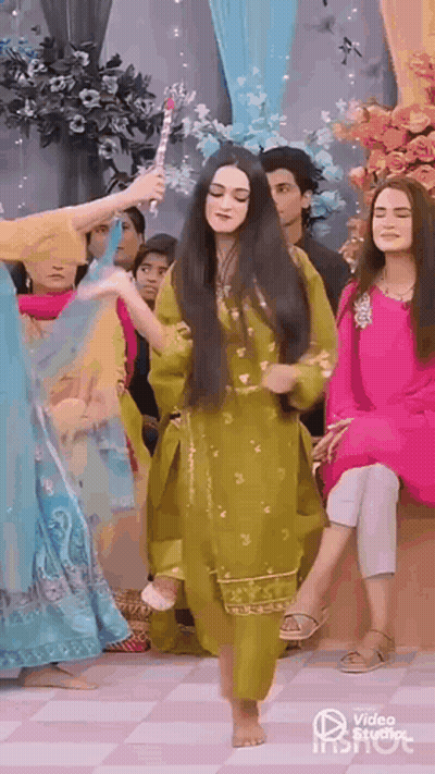 A Woman In A Green Dress Is Dancing Barefoot In Front Of A Group Of People . GIF