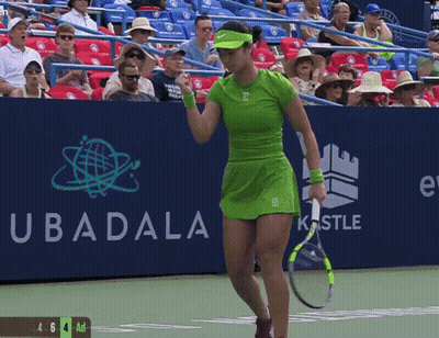 A Woman In A Green Dress Is Holding A Tennis Racquet In Front Of A Sign That Says Ubadala GIF