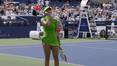 A Woman In A Green Dress Is Holding A Tennis Racquet GIF