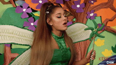 A Woman In A Green Dress Is Holding A Wand And The Word Kidding Is On The Bottom Right GIF