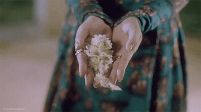 A Woman In A Green Dress Is Holding White Flowers GIF