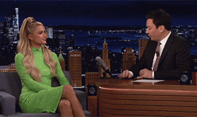 A Woman In A Green Dress Is Sitting In Front Of A Man In A Suit GIF