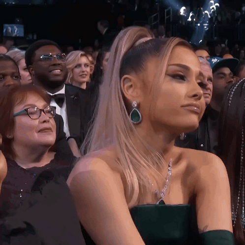 A Woman In A Green Dress Is Sitting In The Audience GIF