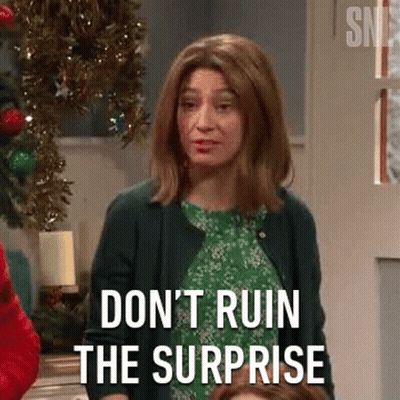 A Woman In A Green Dress Is Standing In Front Of A Christmas Tree And Saying `` Don 'T Ruin The Surprise '' . GIF