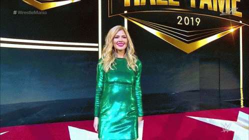 A Woman In A Green Dress Is Standing In Front Of A Sign That Says 2019 GIF