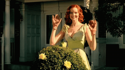 A Woman In A Green Dress Is Standing In Front Of A White House GIF