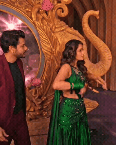 A Woman In A Green Dress Is Standing Next To A Man In A Red Suit . GIF