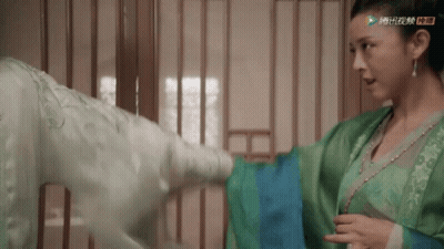A Woman In A Green Dress Is Standing Next To A Man GIF