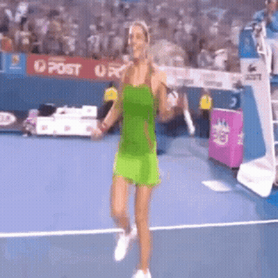 A Woman In A Green Dress Is Walking On A Tennis Court . GIF