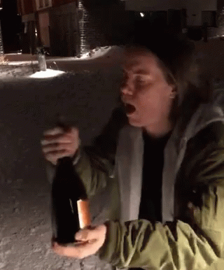 A Woman In A Green Jacket Is Holding A Bottle Of Wine In Her Hand GIF