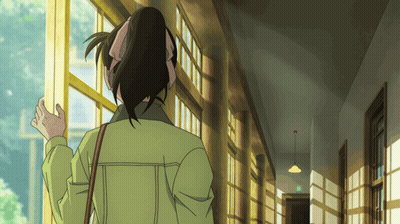 A Woman In A Green Jacket Is Standing In A Hallway Looking Out A Window GIF