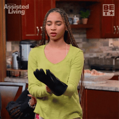 A Woman In A Green Shirt Is Putting On A Black Oven Mitt GIF