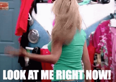 A Woman In A Green Shirt Is Standing In A Closet With The Words Look At Me Right Now On The Bottom GIF