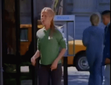 A Woman In A Green Shirt Is Standing In Front Of A Pay Phone Booth GIF