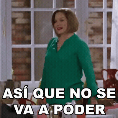 A Woman In A Green Shirt Is Standing In Front Of A Window And Making A Funny Face . GIF