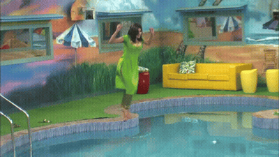A Woman In A Green Shirt Is Swimming In A Pool GIF