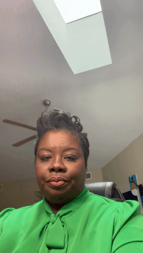 A Woman In A Green Shirt Is Taking A Selfie GIF
