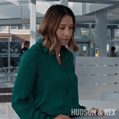 A Woman In A Green Shirt With The Word Hudson & Rex On The Bottom GIF